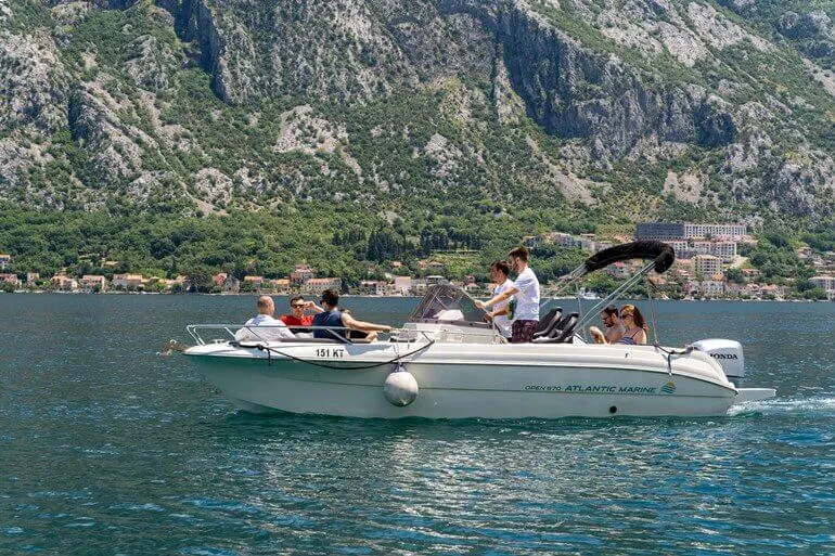 Couple relaxing on a rented boat with Kotor Bay mountains behind Couple relaxing on a rented boat with Kotor Bay mountains behind