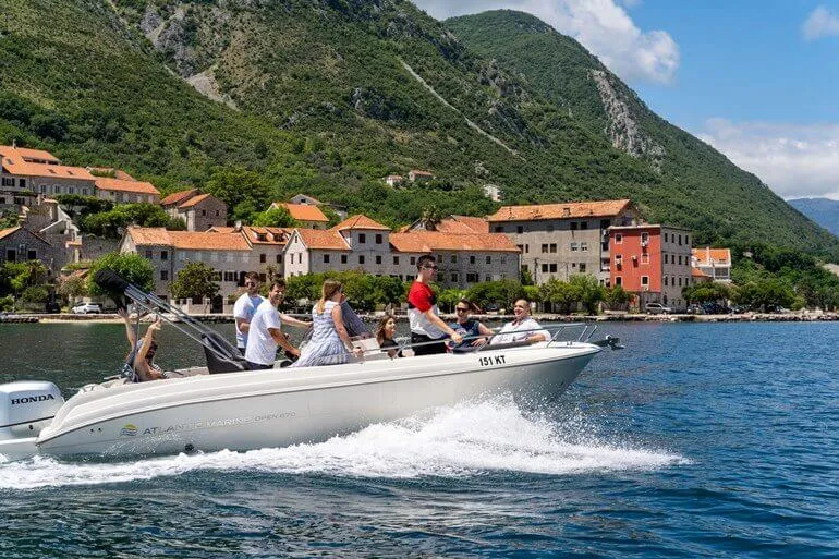 Rental boat approaching a seaside restaurant in the Bay of Kotor Rental boat approaching a seaside restaurant in the Bay of Kotor