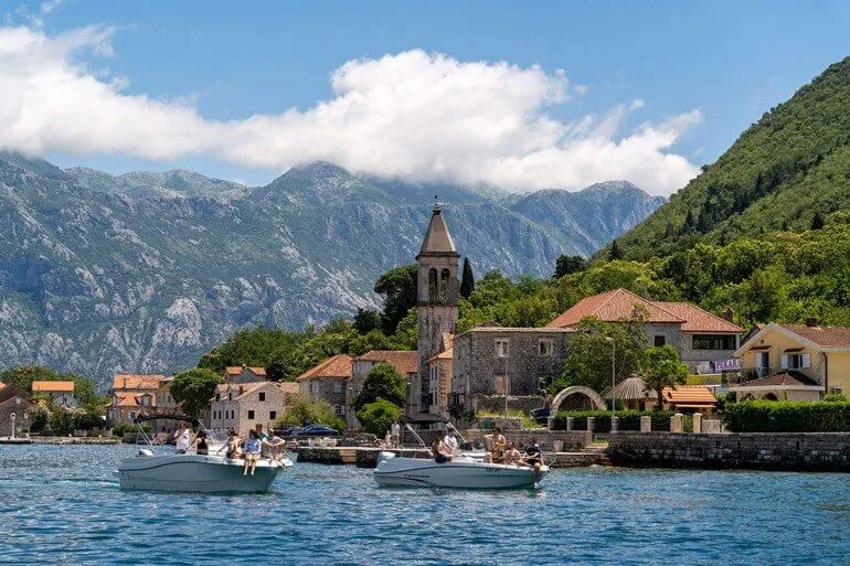Speedboat passing the coastal village of Prcanj in the bay Speedboat passing the coastal village of Prcanj in the bay