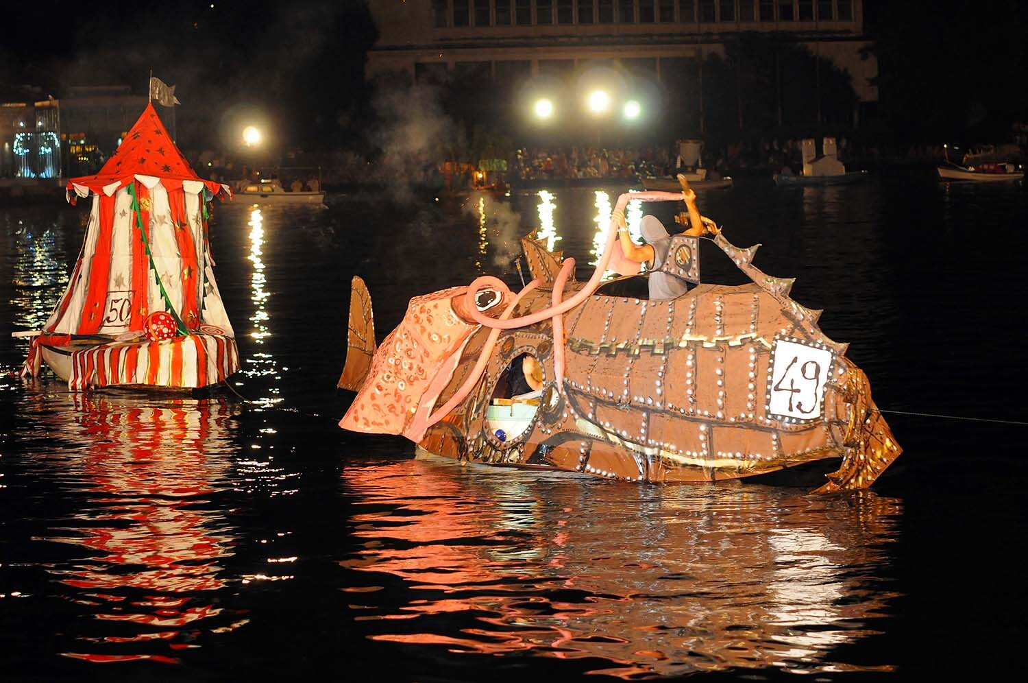 A giant illuminated fish-shaped float and a decorated tent-boat cross Kotor's harbor during the real Boka Night parade